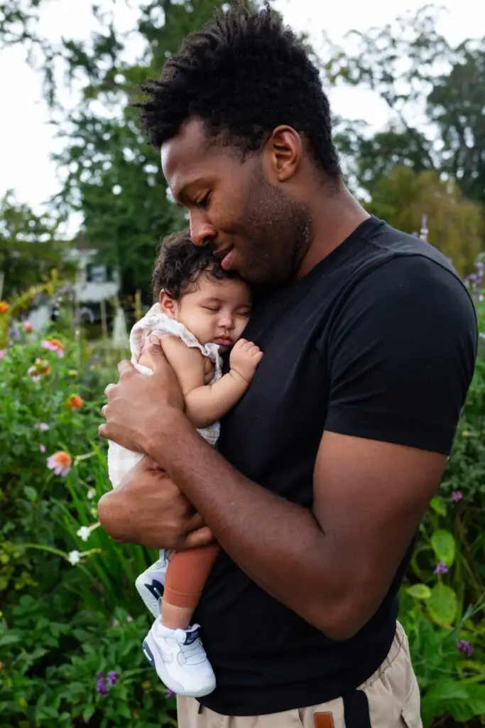 New dad tenderly cradles his baby girl with his cheek against her curls.