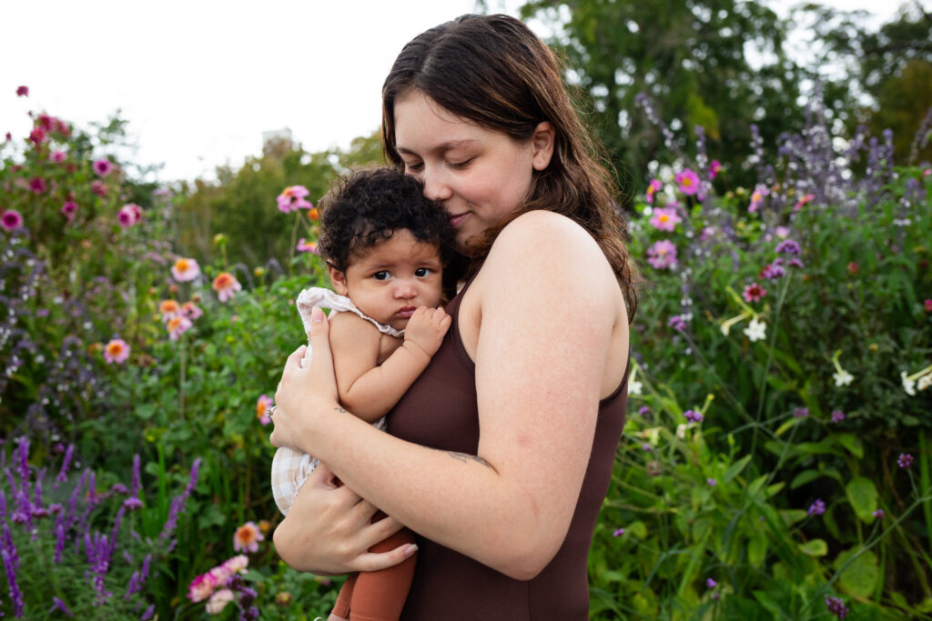 A new mom bonds with her newborn daughter in a beautiful garden.