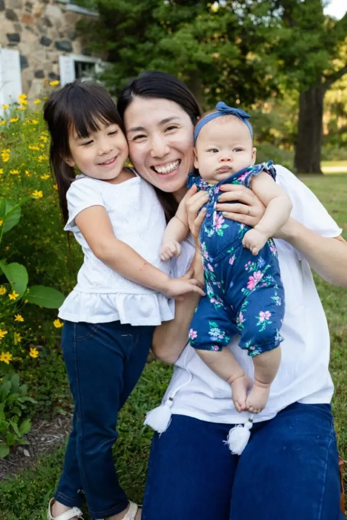 Mom cuddles in with her daughters on a summer evening at the park.